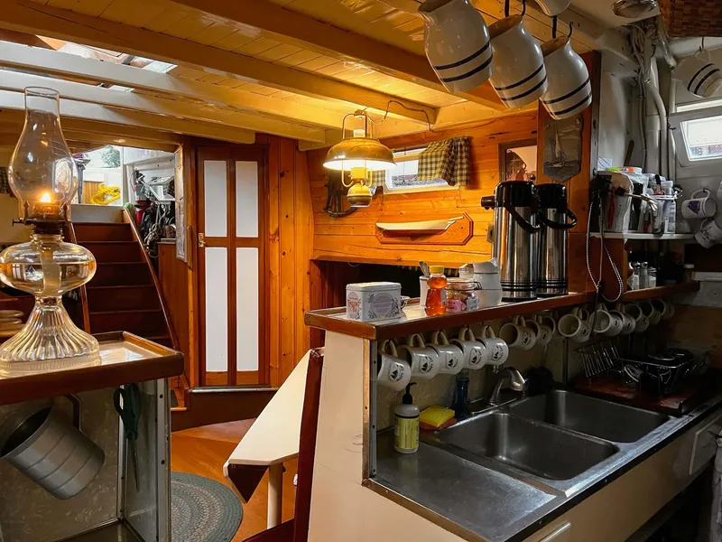 Slide: The Image of Interior of 1962 Gamage Coastal Gaff Rigged Schooner, featuring a cozy wooden kitchen area. - 31
