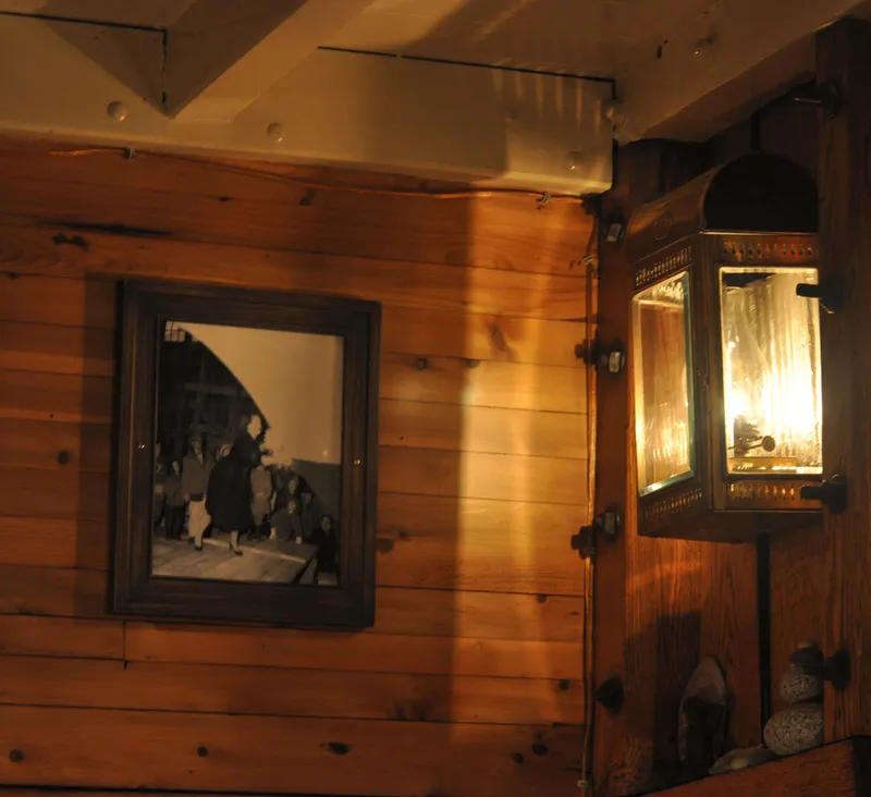 Slide: The Image of Wood-paneled interior with vintage lantern and framed photo on a 1962 Gamage schooner. - 33