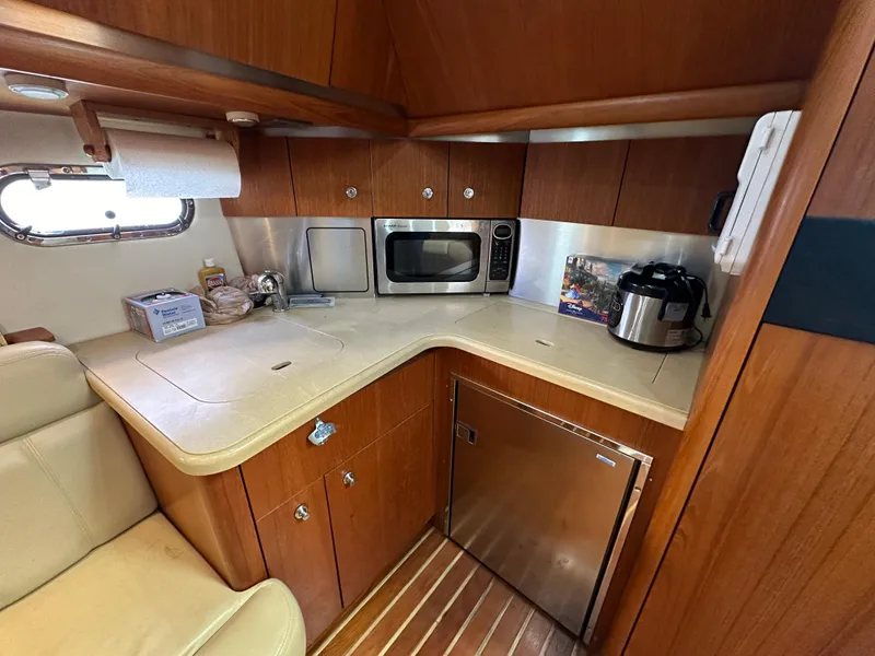 Slide: The Image of 2004 Tiara Yachts 3600 Sovran galley with microwave, fridge, and wooden cabinetry. - 17