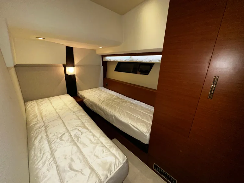 Slide: The Image of Twin beds in a 2013 Prestige 500 yacht cabin with wood paneling and soft lighting. - 26