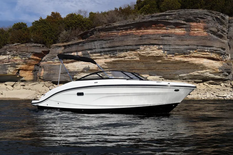 Slide: The Image of 2024 Sea Ray SPX 210 boat cruising near rocky shoreline. - 2