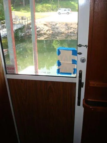 Slide: The Image of 1988 Chris-Craft Constellation boat door with taped window, overlooking water and dock. - 15