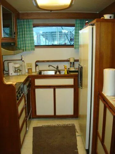 Slide: The Image of 1988 Chris-Craft Constellation kitchen with wooden cabinets, appliances, and a window view. - 31