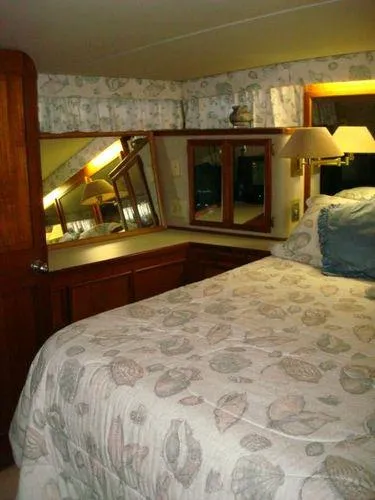 Slide: The Image of 1988 Chris-Craft Constellation bedroom with floral bedding, wooden cabinetry, and mirrored vanity. - 39