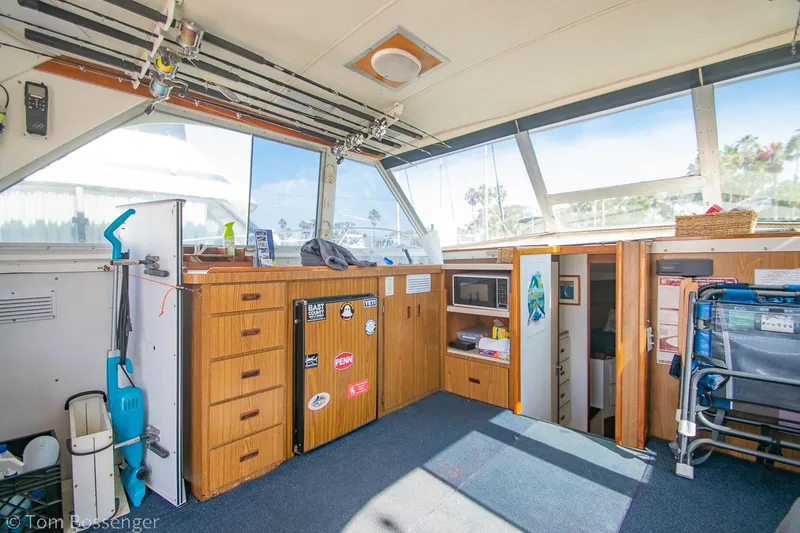 Slide: The Image of 1976 Bertram 35 Convertible interior with wooden cabinets, microwave, and cleaning equipment. - 11