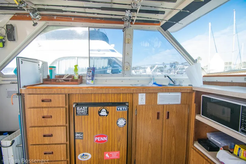 Slide: The Image of Interior of a 1976 Bertram 35 Convertible boat with wooden cabinets and a microwave. - 13