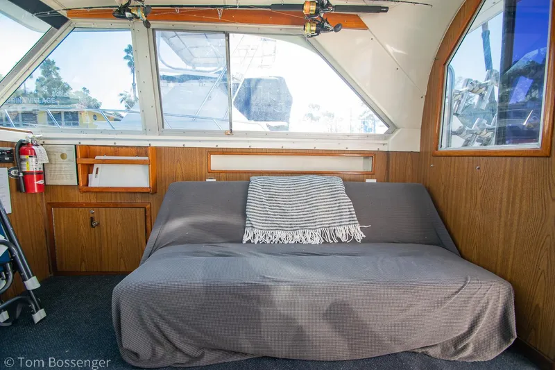 Slide: The Image of 1976 Bertram 35 Convertible interior with sofa, striped blanket, and wooden paneling. - 15