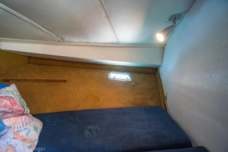 Slide: The Image of 1976 Bertram 35 Convertible cabin interior with cozy bedding and small window. - 22