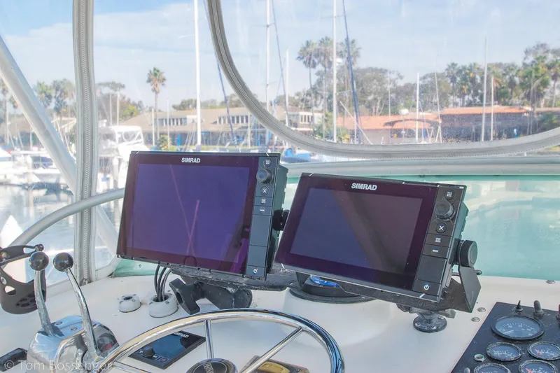Slide: The Image of Helm of 1976 Bertram 35 Convertible with dual Simrad displays and marina view. - 31