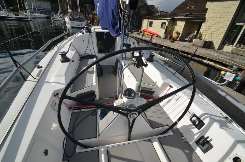 Slide: The Image of 2011 J Boats J/111 sailboat cockpit with steering wheel and docked marina background. - 12