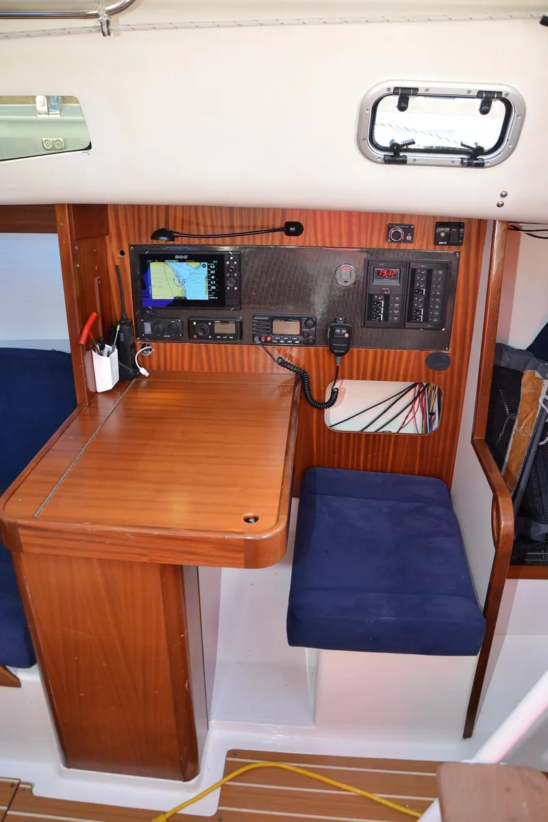 Slide: The Image of 2011 J Boats J/111 navigation station with wood finish and blue cushioned seat. - 22