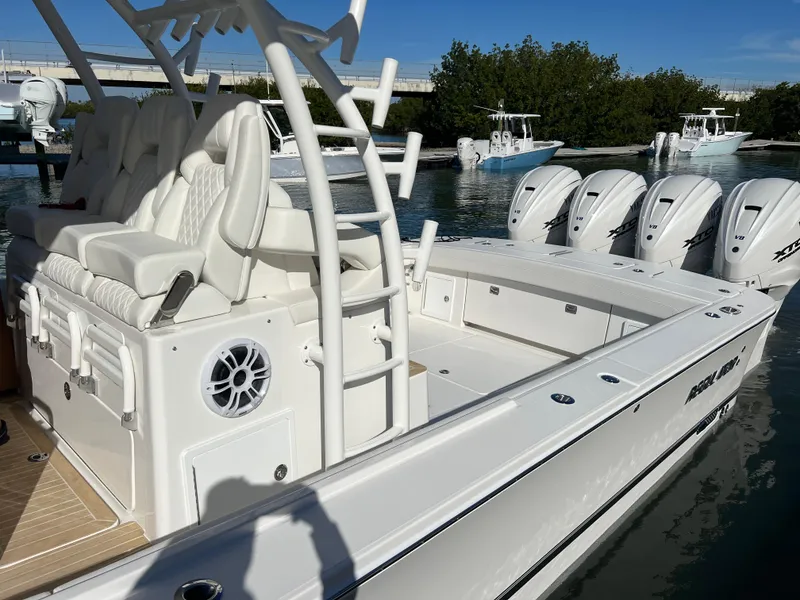 Slide: The Image of 2024 Regulator 41 boat with four engines, white seating, and sleek design docked by water. - 12