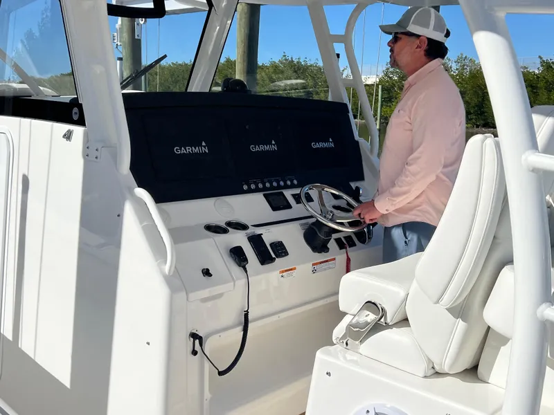 Slide: The Image of 2024 Regulator 41 boat helm with Garmin displays and a person steering. - 14