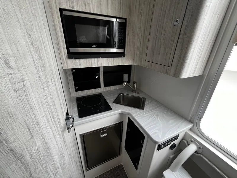 Slide: The Image of 2024 Regulator 41 boat kitchen with microwave, stove, sink, and compact fridge. - 44
