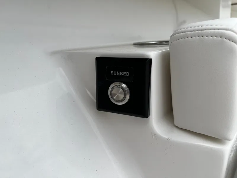 Slide: The Image of Regulator 41 2024 boat sunbed control button and white cushioned seat. - 48