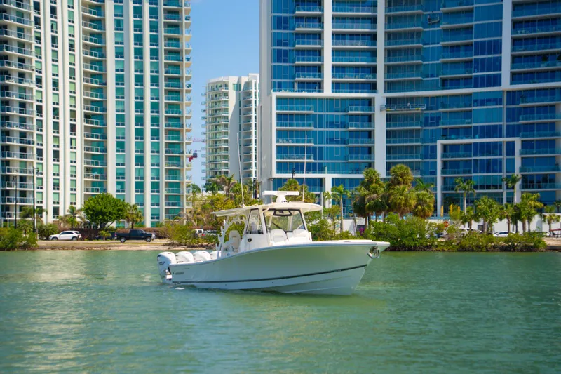 Slide: The Image of 2024 Regulator 41 boat cruising near modern high-rise buildings and palm trees. - 58