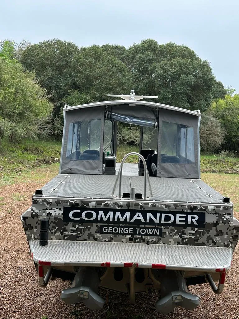 Slide: The Image of 2014 Wooldridge 31 Commander boat with camouflage design, parked on gravel. - 14