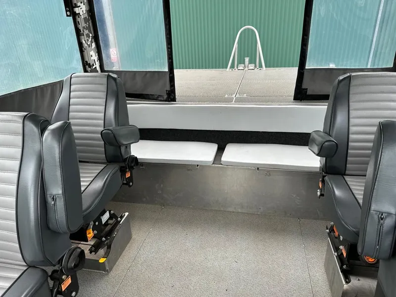 Slide: The Image of Interior of a 2014 Wooldridge 31 boat with four grey seats and large windows. - 6