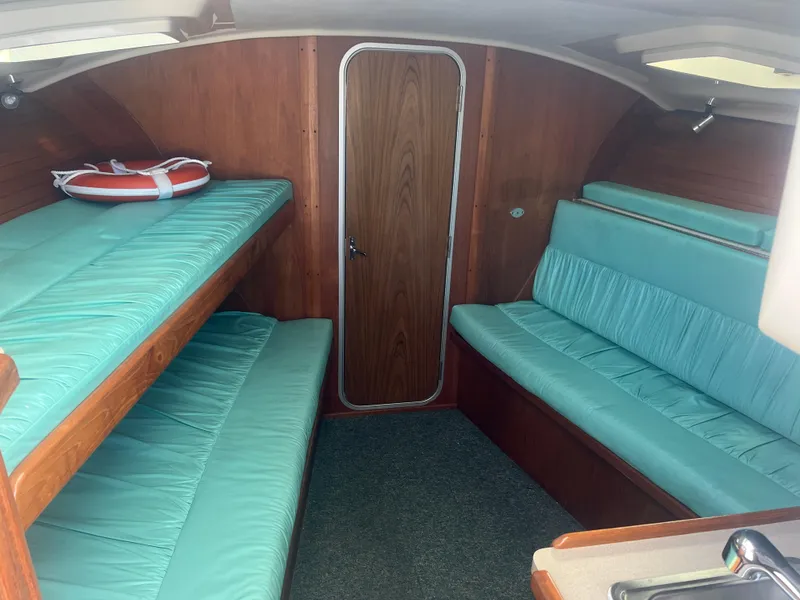 Slide: The Image of 1995 Luhrs Tournament 290 Open cabin interior with teal cushions and wooden finishes. - 17