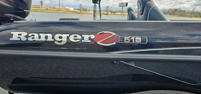 Slide: The Image of 2017 Ranger 518 boat with logo detail, parked near a lake. - 2