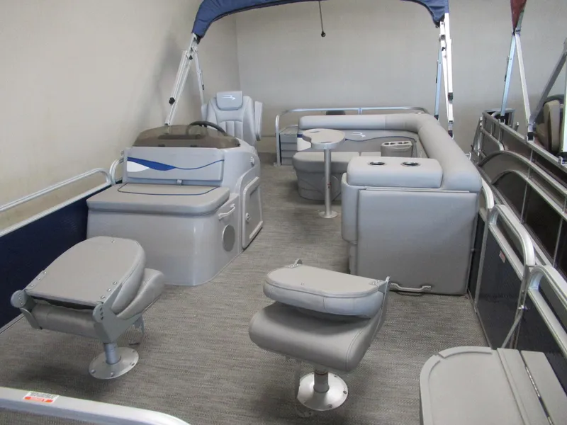 Slide: The Image of 2024 Bennington 20 SVF pontoon boat interior with gray seating and blue canopy. - 2