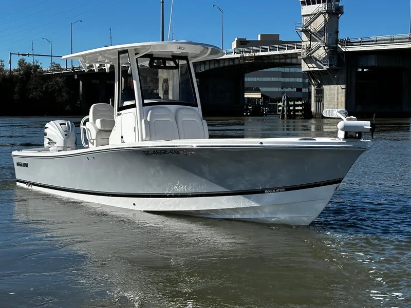 The Image of A white boat floating on a calm river in front of a bridge. - 0