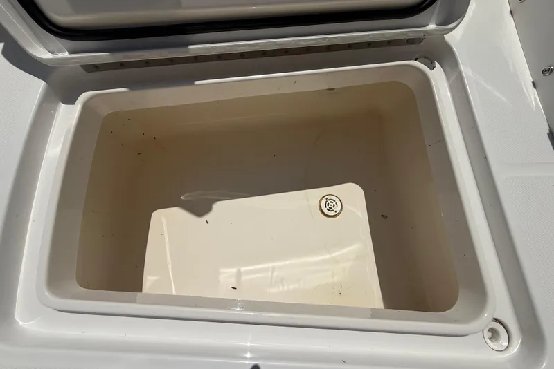 Slide: The Image of Open storage compartment on 2023 Regulator 26XO boat, featuring a drain plug. - 42