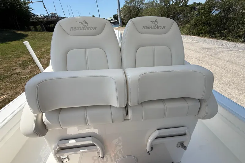 Slide: The Image of 2023 Regulator 26XO boat seats, white leather, outdoor setting. - 25