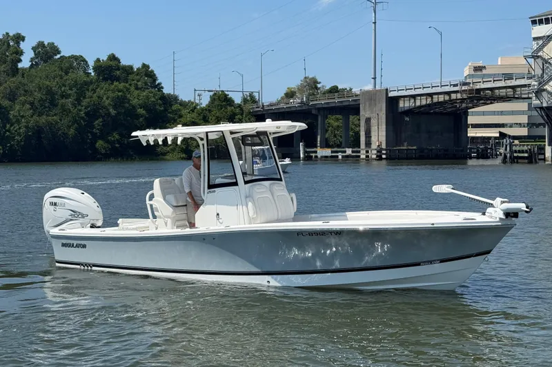 Slide: The Image of 2023 Regulator 26XO boat cruising on a river near a bridge. - 1