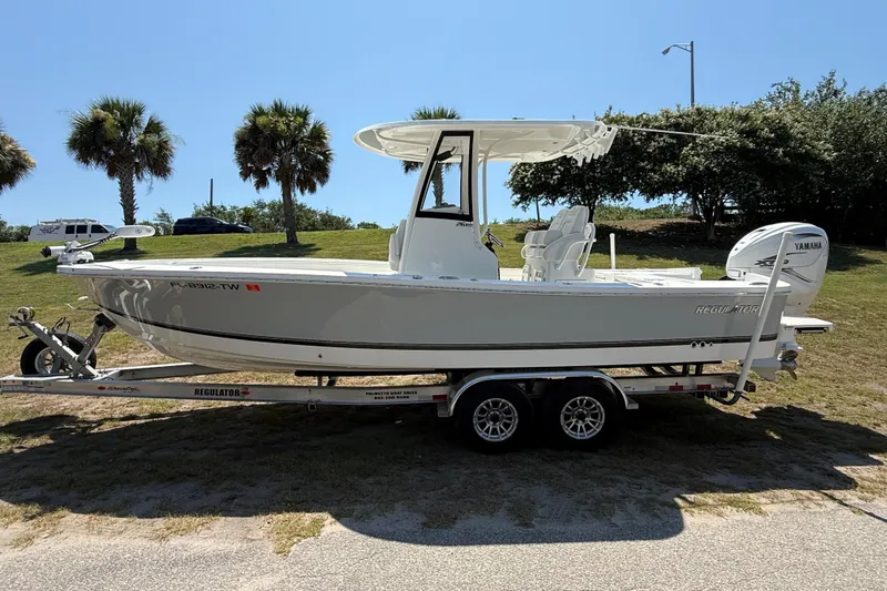 Slide: The Image of 2023 Regulator 26XO boat on trailer, parked outdoors with palm trees in background. - 9