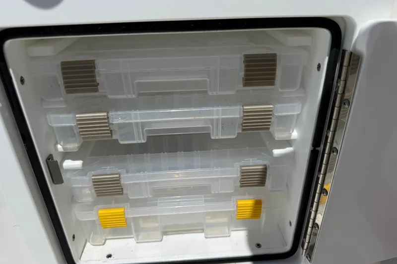 Slide: The Image of Storage compartment with clear plastic trays in a 2023 Regulator 26XO boat. - 52