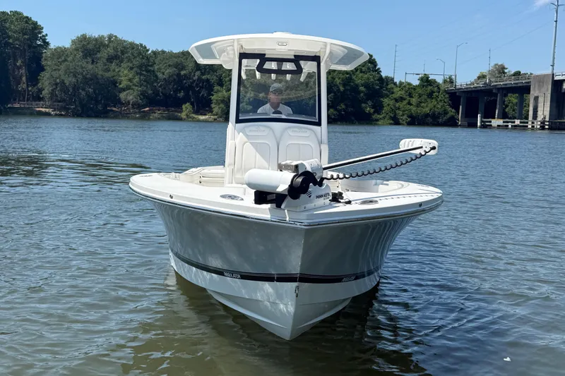 Slide: The Image of 2023 Regulator 26XO boat on calm water near a bridge and trees. - 2