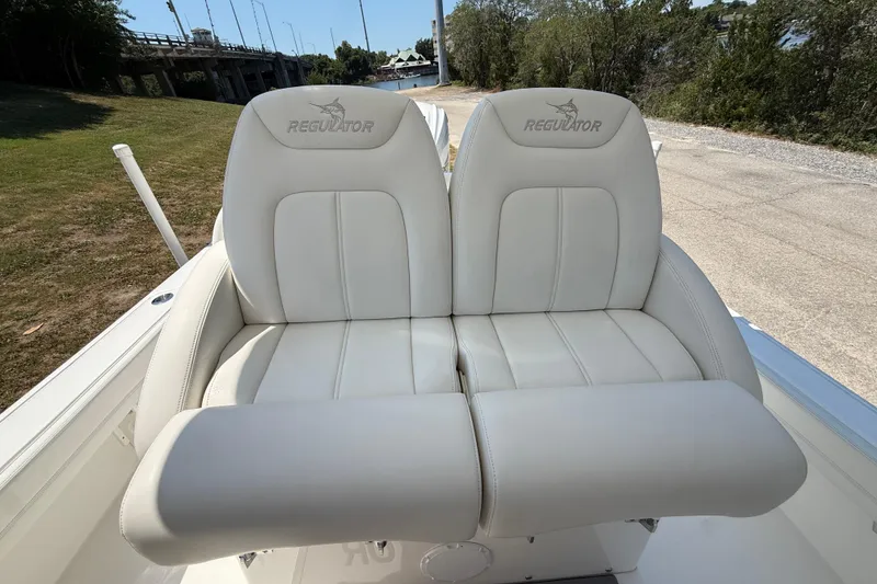 Slide: The Image of 2023 Regulator 26XO boat seats, white leather, outdoor setting. - 24