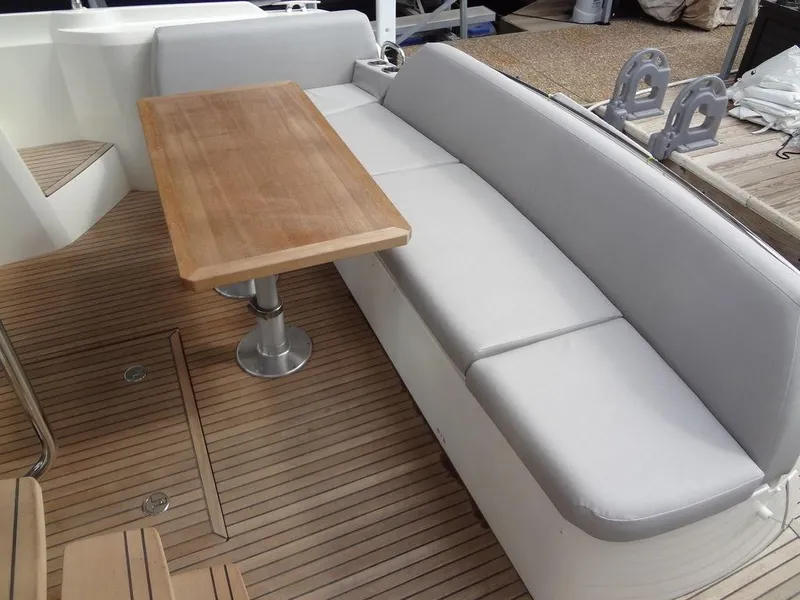 Slide: The Image of Prestige 420F 2024 boat deck with cushioned seating and wooden table. - 22