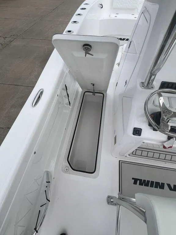 Slide: The Image of 2024 Twin Vee 280 STX boat interior with open storage compartment and steering wheel. - 21