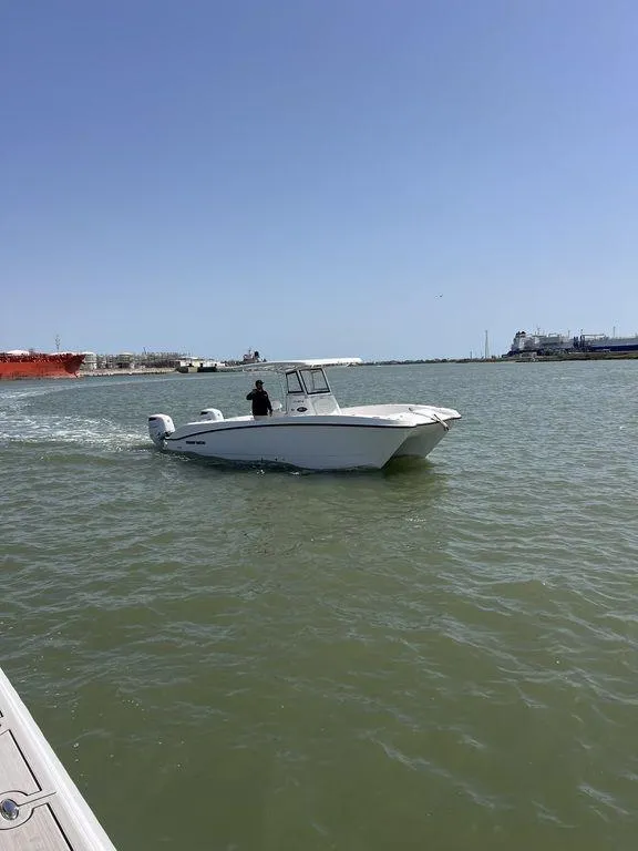 Slide: The Image of 2024 Twin Vee 280 STX boat cruising on a calm waterway under a clear blue sky. - 30