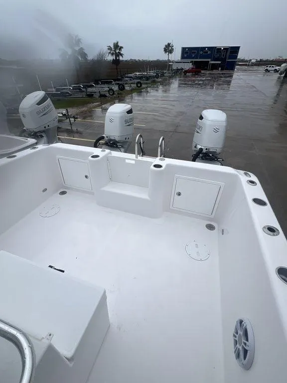 Slide: The Image of 2024 Twin Vee 280 STX boat deck with outboard motors, in a marina setting. - 9