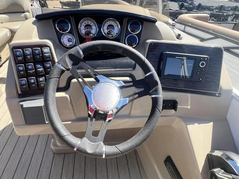Slide: The Image of 2023 Starcraft CX 25 DL BAR boat dashboard with steering wheel and control panel. - 16