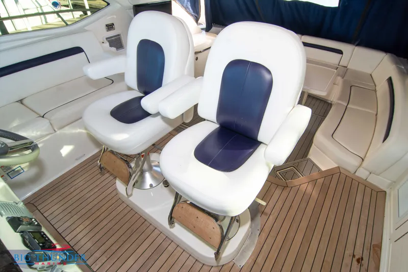 Slide: The Image of 2010 Sea Ray 540 Sundancer interior with white and blue captain chairs on teak flooring. - 43