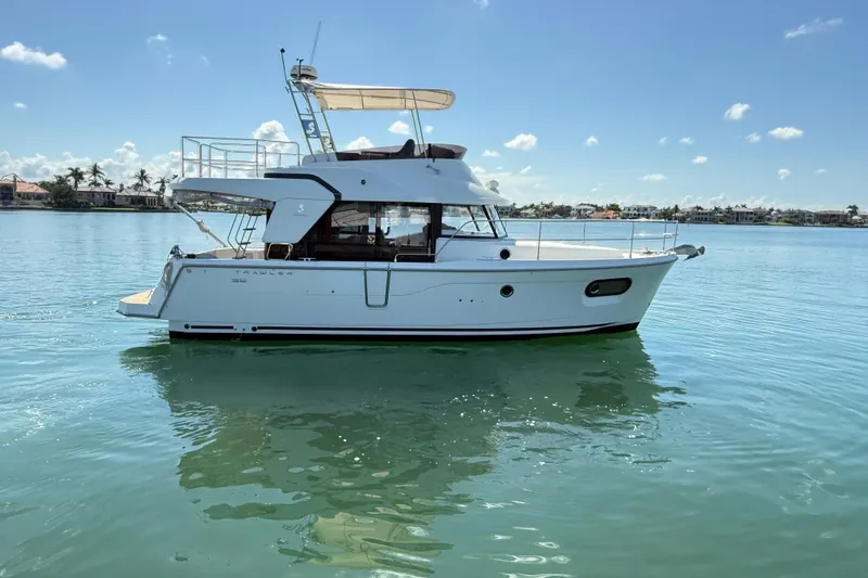 Slide: The Image of 2021 Beneteau Swift Trawler 35 on calm water under clear blue sky. - 1
