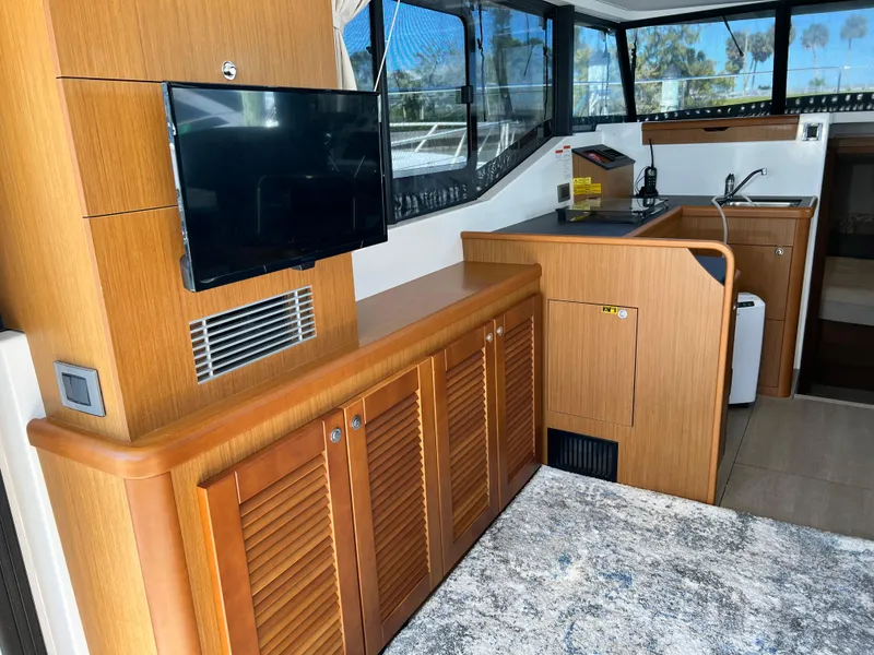 Slide: The Image of Interior of 2021 Beneteau Swift Trawler 35 with TV, wooden cabinets, and kitchenette. - 15
