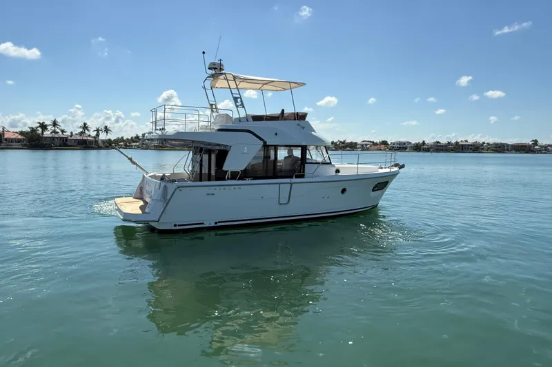 Slide: The Image of 2021 Beneteau Swift Trawler 35 cruising on calm waters under a clear blue sky. - 2