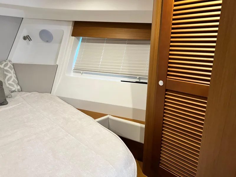 Slide: The Image of 2021 Beneteau Swift Trawler 35 bedroom with window, bed, and wooden closet. - 27