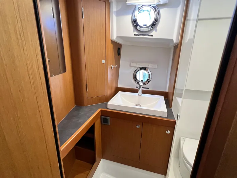 Slide: The Image of 2021 Beneteau Swift Trawler 35 bathroom with wooden cabinetry and porthole windows. - 34