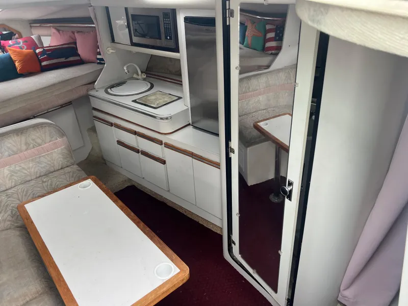 Slide: The Image of 1991 Cruisers Yachts Rouge 33 interior with kitchenette, dining area, and cozy seating. - 23