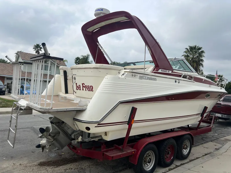 Slide: The Image of 1991 Cruisers Yachts Rouge 33 on a red trailer, parked in a residential area. - 4
