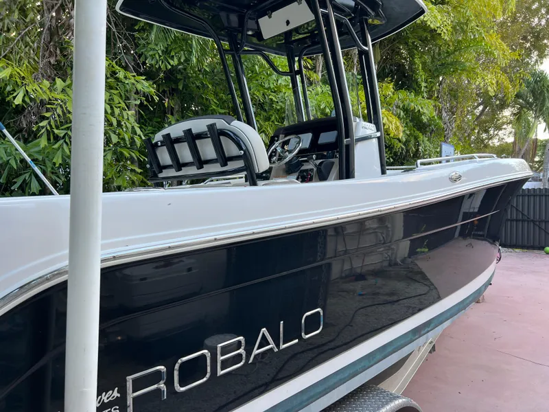 Slide: The Image of 2018 Robalo R242 Center Console boat docked near lush greenery. - 10