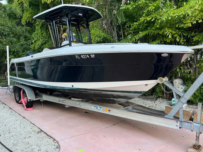 Slide: The Image of 2018 Robalo R242 Center Console boat on a trailer, parked outdoors. - 2