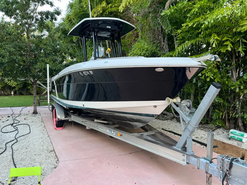 Slide: The Image of 2018 Robalo R242 Center Console boat on a trailer in a lush backyard. - 3