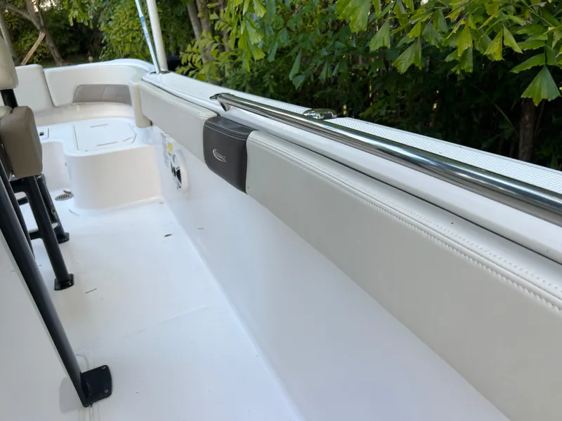 Slide: The Image of 2018 Robalo R242 Center Console boat interior with white seating and greenery background. - 45